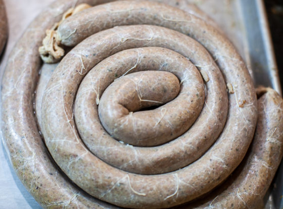 coil of Boudin sausage in casing on sheet pan