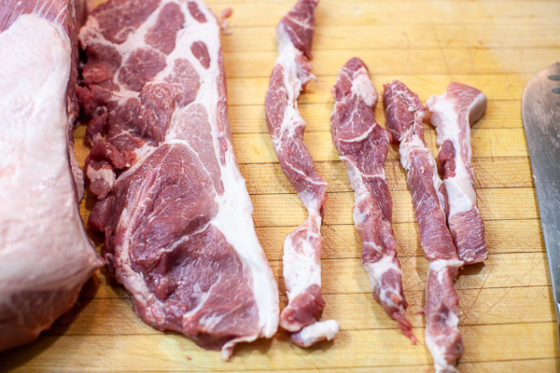 pork slices cut into strips on wooden cutting board