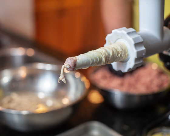 knot tied on end of sausage casing over sausage stuffer
