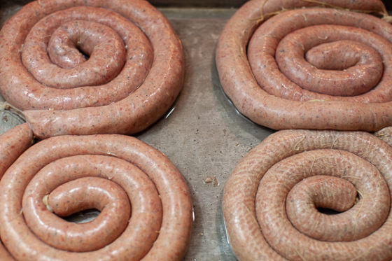 four large coils of sausage on a sheet pan with water