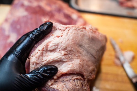 gloved hand holding brisket with fat side up