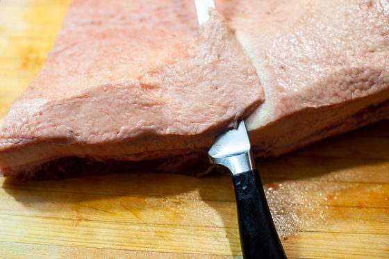 slicing fat off the top of a brisket