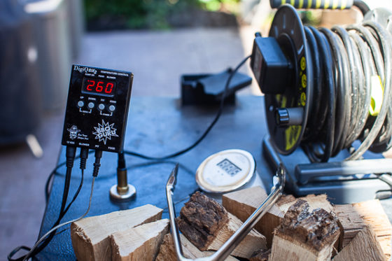 thermometer reading 260 degrees F, wood chunks, tongs, extension cord on top of smoker
