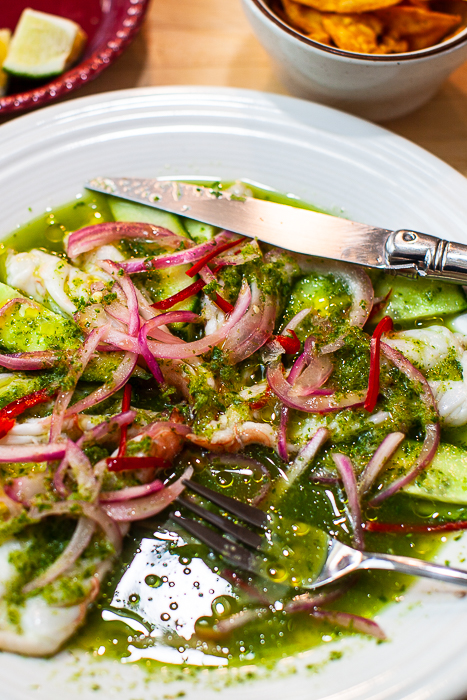 aguachile de camaron on plate with fork, knife and drizzled olive oil