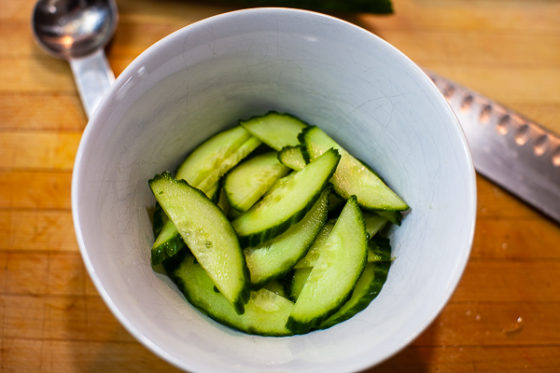 half moon slices of english cucumber in white bowl