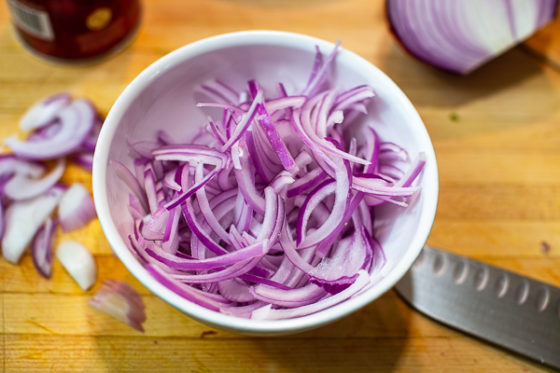 julienned slices of red onion in white bowl