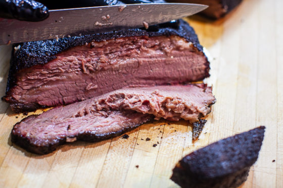 Slicing smoked brisket on wooden cutting board