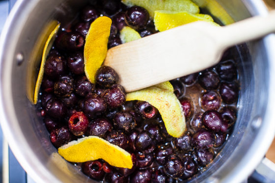 cherries in sauce pot with lemon zest, and juice, stirred with wooden spoon