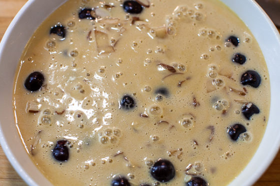 dish containing milk and egg mixture over cherries, almonds and peaches