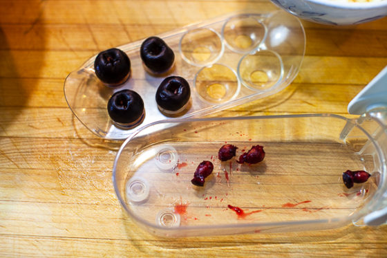 four cherries in pitter with pits removed on a cutting board