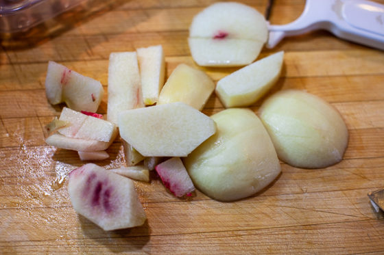 peaches cut in chunks around pit on wooden cutting board
