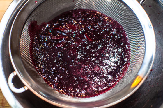 blended cherries being pass through mesh strainer
