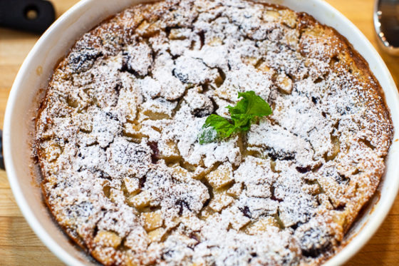 dish containing cooked clafoutis dusted with powdered sugar, mint sprig 