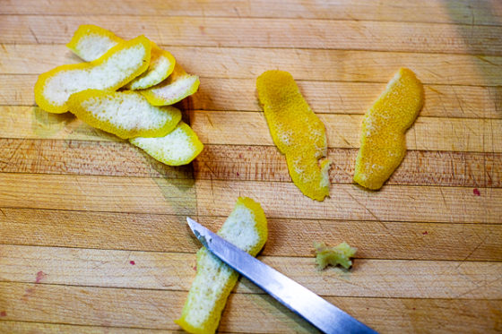 strips of lemon on cutting board, knife scraping pith