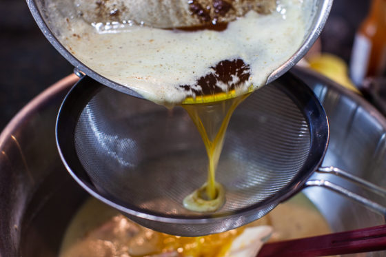 brown butter being poured through sieve