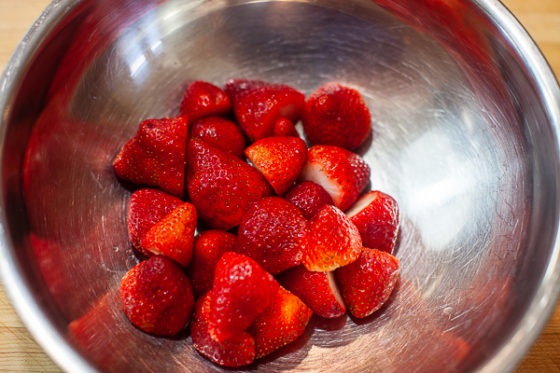 metal mixing bowl containing hulled strawberries