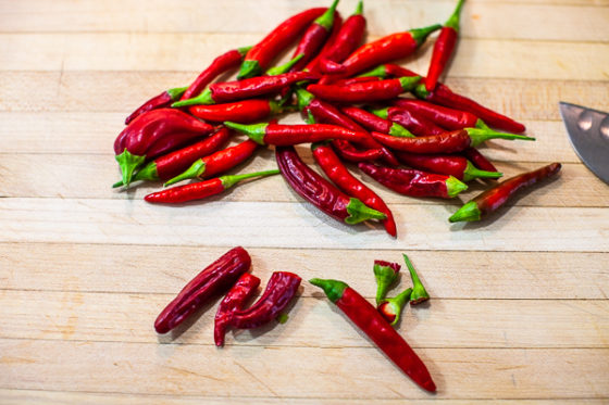 chile pepper grouped together on cutting board with tops chopped off