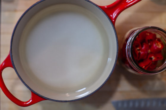 pot containing vinegar, sugar and salt next to jar of chiles