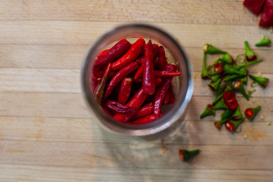 chile peppers with tops removed in a glass jar