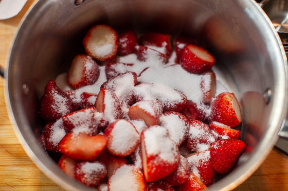 metal mixing bowl containing strawberries and sugar