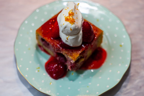 square of strawberry financier cake with strawberry compote and whipped cream on plate