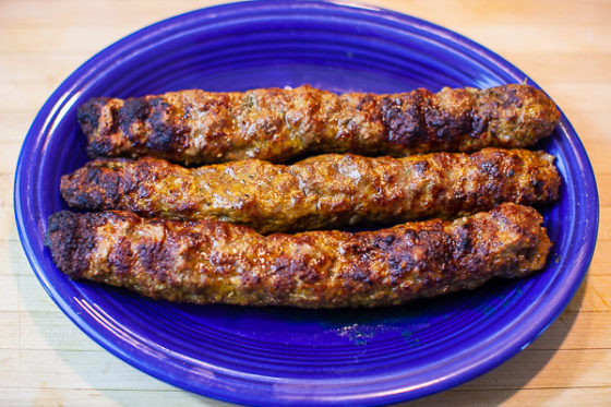 oval blue platter containing three long cooked kebabs