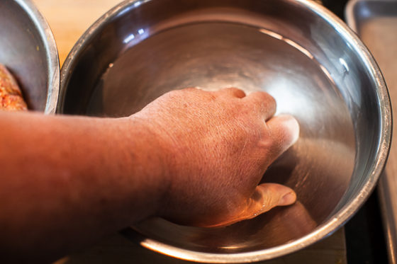 hand immersed in metal mixing bowl containing water