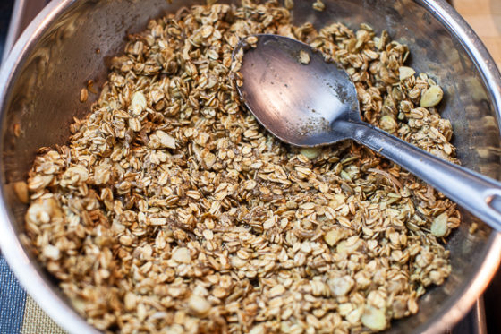 granola mixture in mixing bowl with water added and spoon used to mix