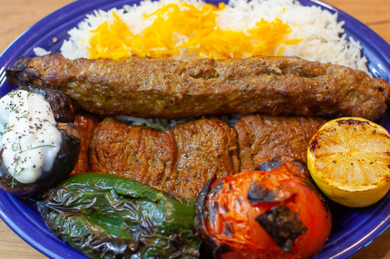 plate of Koobideh, Barb Kebab, rice, grilled pepper, tomato, lemon, eggplant, dill yogurt sauce
