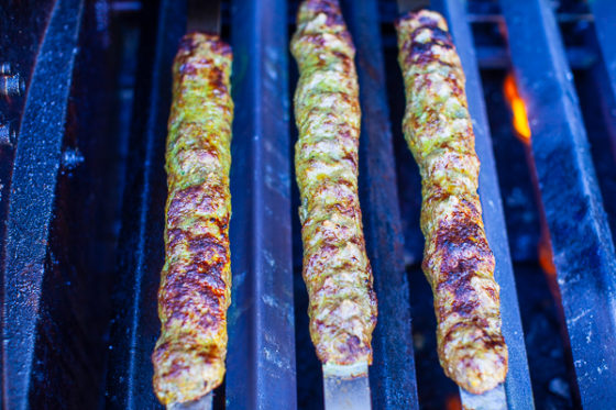 three slightly charred kebabs over low-medium flame