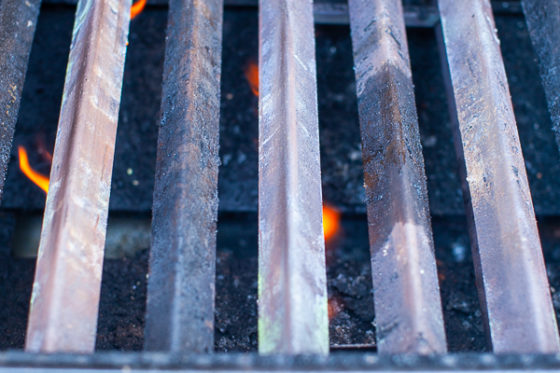 gas grill with grates removed, yellow flame