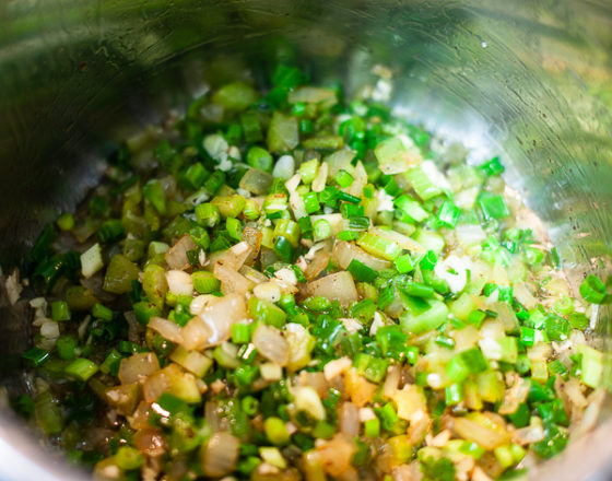 Onions, celery, green pepper, garlic, seasoning in a pot with bacon drippings.