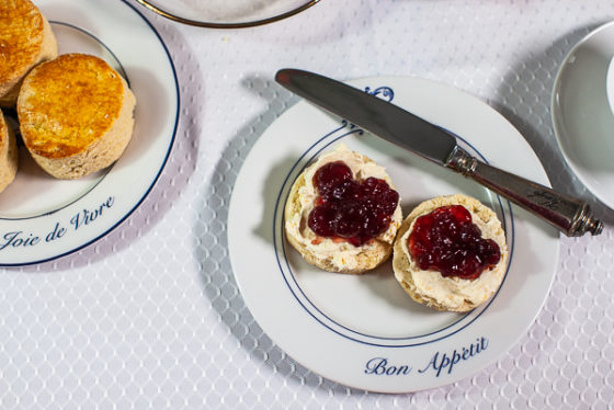 plate with halved english scone, clotted cream and strawberry jam