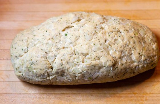 Forming a loaf of Swedish dill bread on wooden cutting board