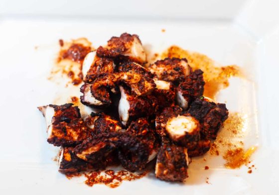 Chunks of grilled Octopus on a white plate.